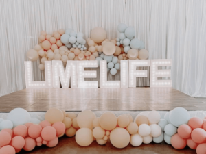 White Marquee letters saying "Limelife" on event stage with pastel balloons