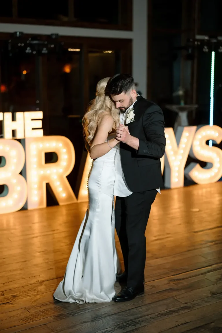 Bride and groom on dance floor with marquee letters behind them saying "The Bradys"