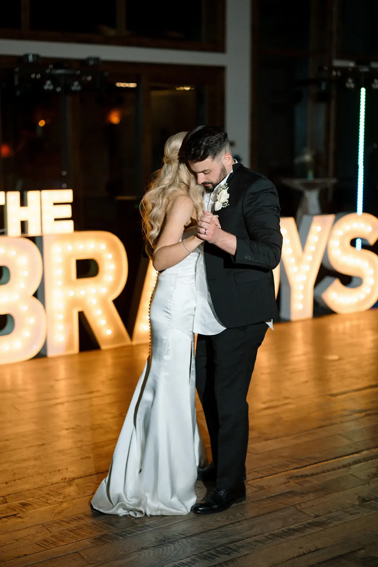 Bride and groom on dance floor with marquee letters behind them saying "The Bradys"